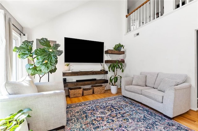 living room with high vaulted ceiling and wood finished floors