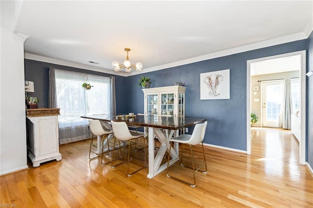 dining room featuring light wood-style floors, a chandelier, and crown molding