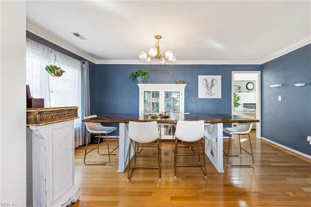 dining room featuring a chandelier, visible vents, light wood-style floors, ornamental molding, and breakfast area