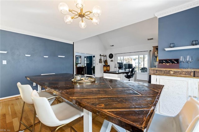 dining room with lofted ceiling, ornamental molding, wood finished floors, a chandelier, and baseboards