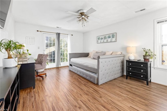 bedroom featuring access to outside, visible vents, and wood finished floors