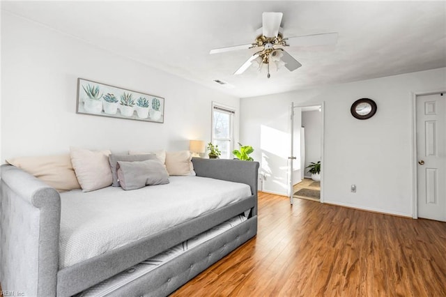 bedroom featuring ceiling fan, wood finished floors, visible vents, and baseboards