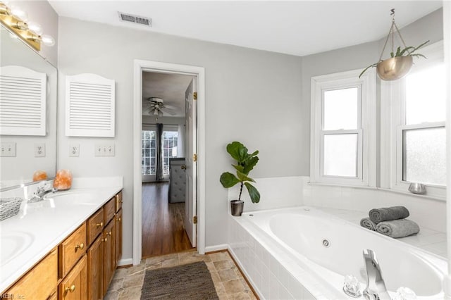 full bath with double vanity, a jetted tub, visible vents, and a sink