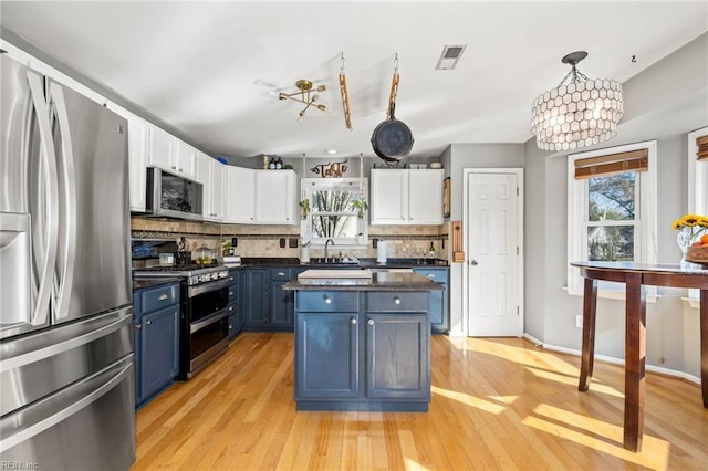 kitchen with visible vents, white cabinets, dark countertops, stainless steel appliances, and blue cabinetry