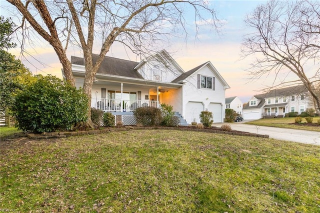 view of front of house featuring an attached garage, a porch, concrete driveway, and a yard