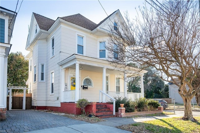 view of front of property featuring a porch, a shingled roof, and fence