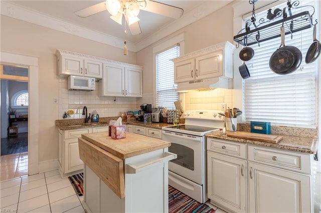 kitchen featuring under cabinet range hood, white appliances, a sink, white cabinetry, and crown molding