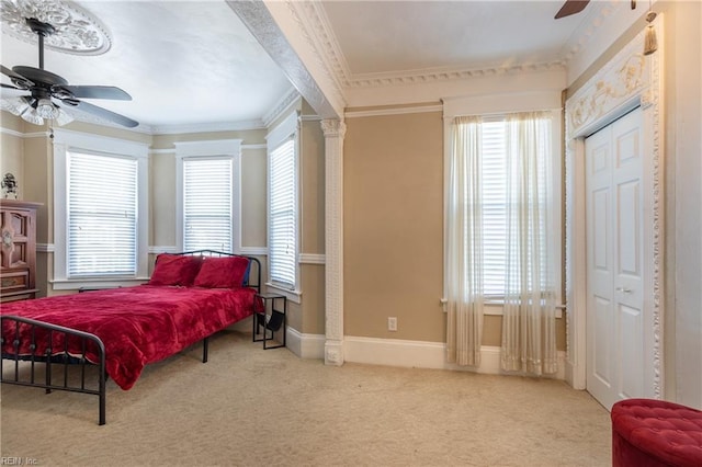 bedroom with light carpet, decorative columns, baseboards, ceiling fan, and crown molding