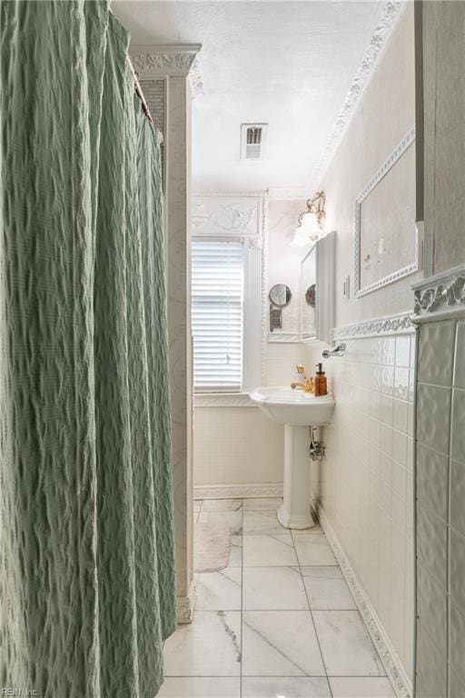 full bathroom featuring a shower with curtain, marble finish floor, visible vents, and tile walls