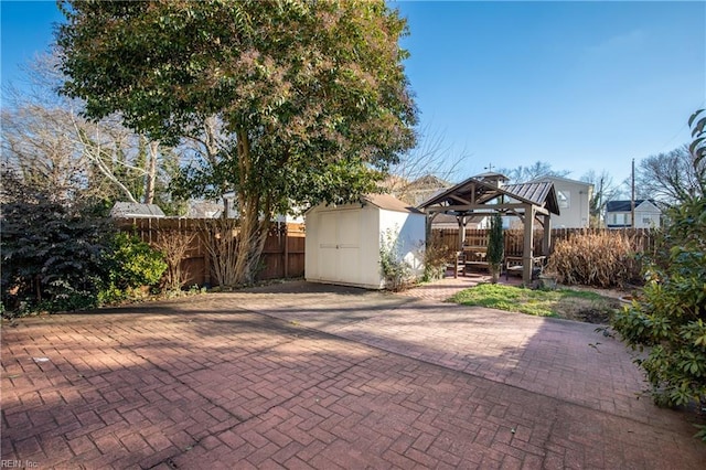 view of patio / terrace with a fenced backyard, an outdoor structure, a gazebo, and a shed