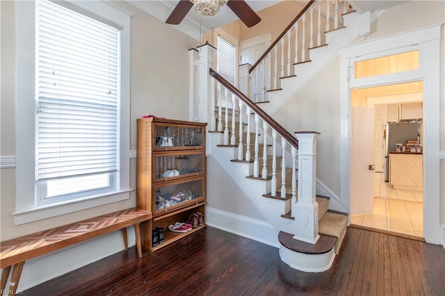 stairway with a ceiling fan, baseboards, ornamental molding, and hardwood / wood-style floors