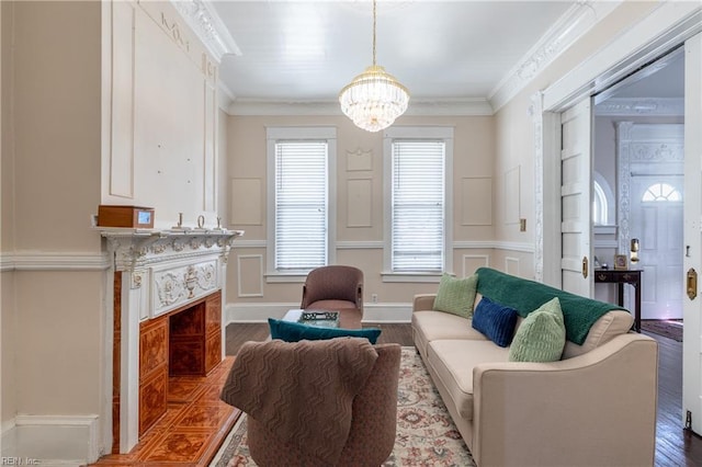 living area with ornamental molding, a fireplace, light wood-style flooring, and an inviting chandelier