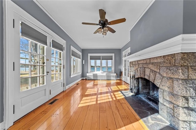 unfurnished sunroom with a ceiling fan, visible vents, a fireplace, and radiator heating unit