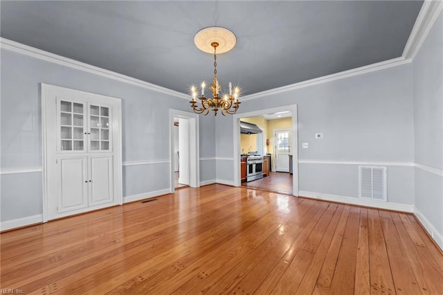 unfurnished dining area with baseboards, visible vents, ornamental molding, light wood-style floors, and a notable chandelier