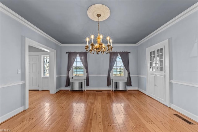 unfurnished dining area with a chandelier, light wood-type flooring, visible vents, and radiator heating unit