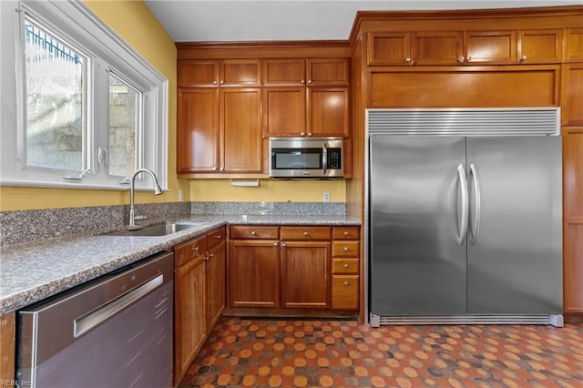 kitchen with brown cabinets, dark floors, stainless steel appliances, and a sink