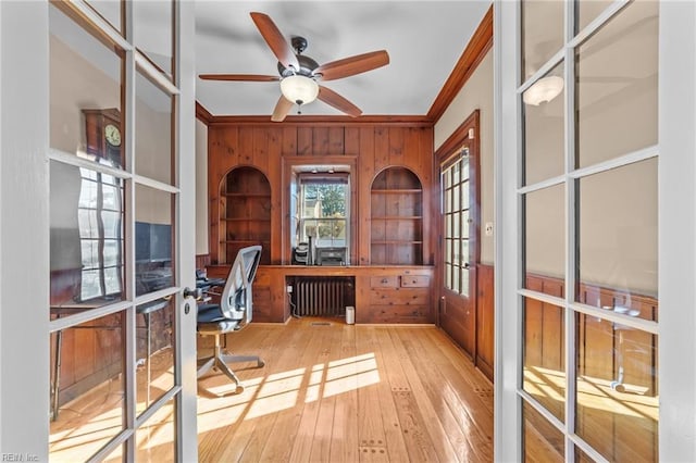 office space with wooden walls, a ceiling fan, hardwood / wood-style flooring, radiator heating unit, and crown molding