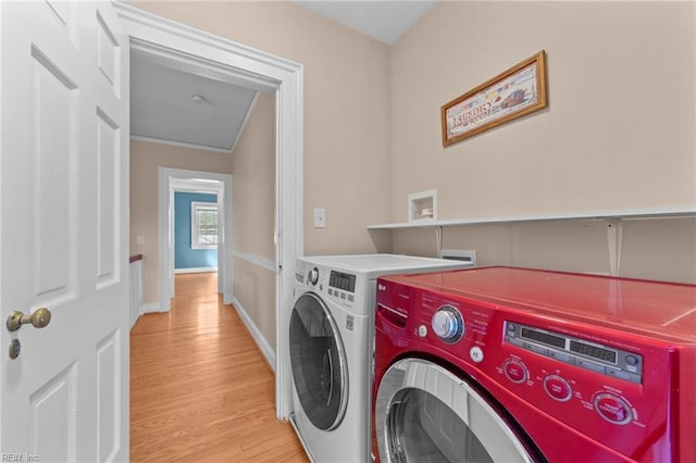 laundry area with light wood-type flooring, washer and dryer, laundry area, and baseboards