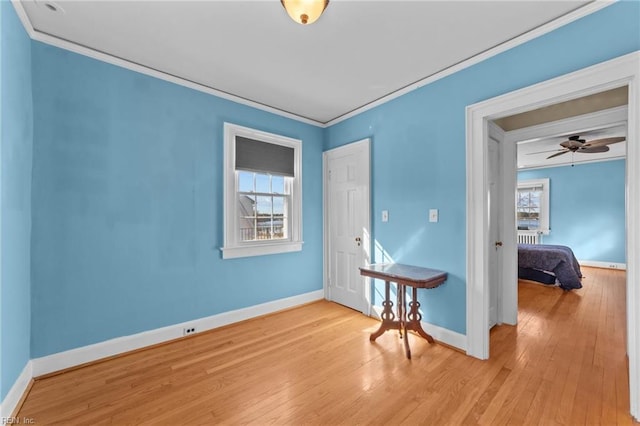 spare room with a wealth of natural light, baseboards, light wood finished floors, and crown molding