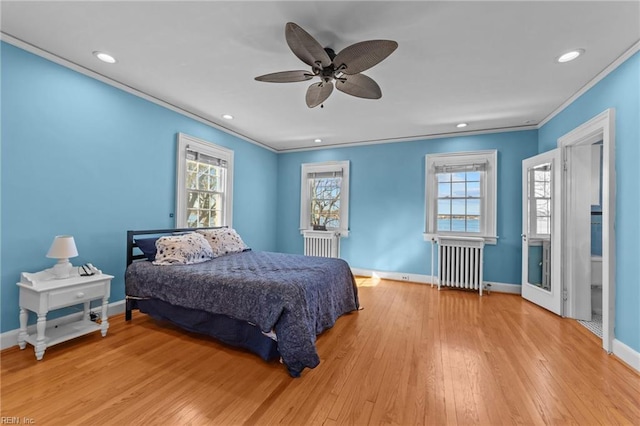 bedroom with radiator heating unit, crown molding, baseboards, and hardwood / wood-style floors