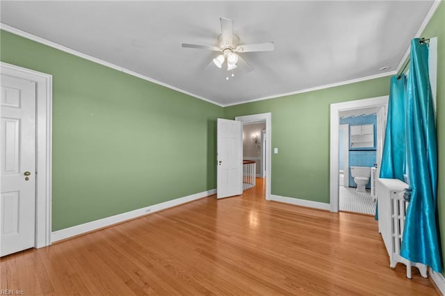 unfurnished bedroom with crown molding, a ceiling fan, ensuite bath, wood finished floors, and baseboards