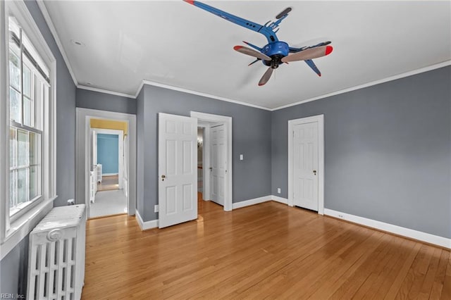 unfurnished bedroom featuring baseboards, crown molding, light wood finished floors, and radiator heating unit