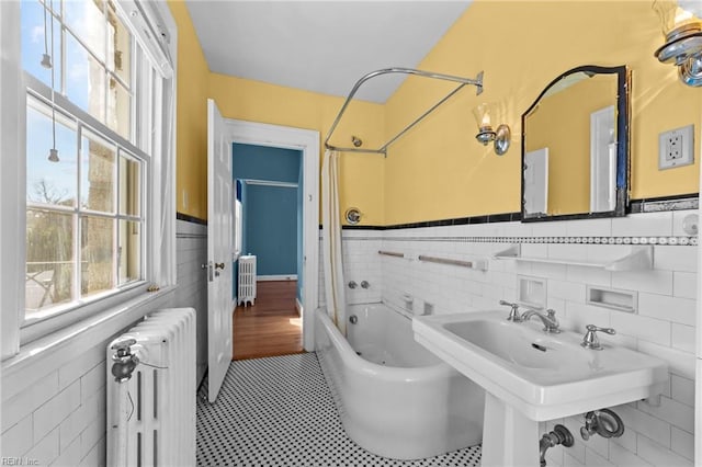 bathroom with a sink, radiator heating unit, wainscoting, and shower / bath combo with shower curtain