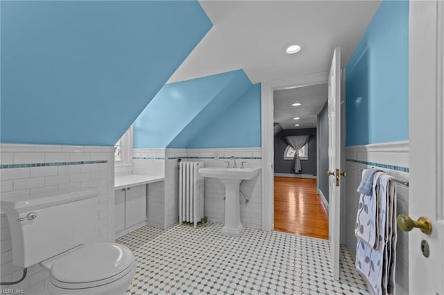 bathroom with a wainscoted wall, tile walls, lofted ceiling, toilet, and radiator heating unit