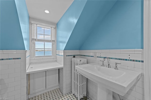 bathroom featuring vaulted ceiling, radiator heating unit, wainscoting, and a sink