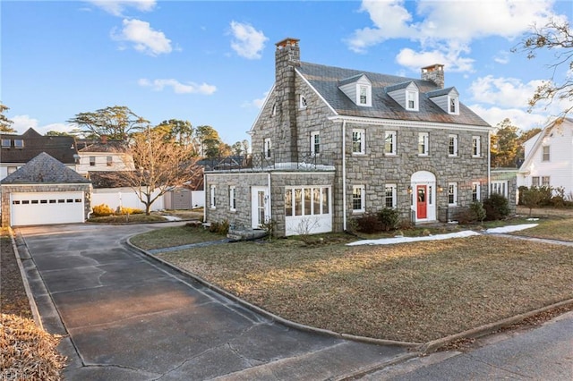 view of front of home with a garage, a chimney, a front yard, and a high end roof