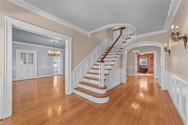 entryway featuring an inviting chandelier, light wood-style flooring, and arched walkways