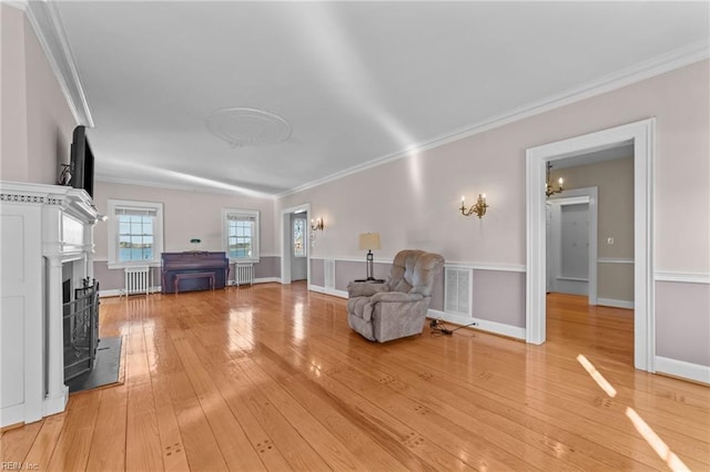 unfurnished room featuring crown molding, visible vents, light wood-style flooring, radiator heating unit, and baseboards