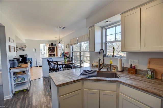 kitchen with a wealth of natural light, a sink, a peninsula, and light stone countertops