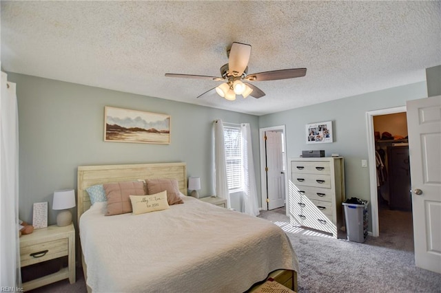 carpeted bedroom with a ceiling fan, a closet, a spacious closet, and a textured ceiling