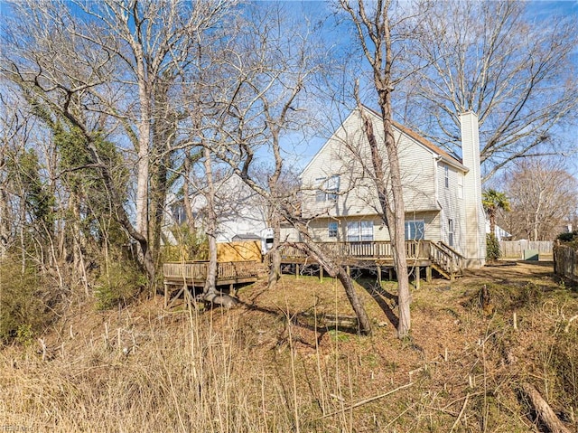 back of property with a chimney, fence, and a wooden deck