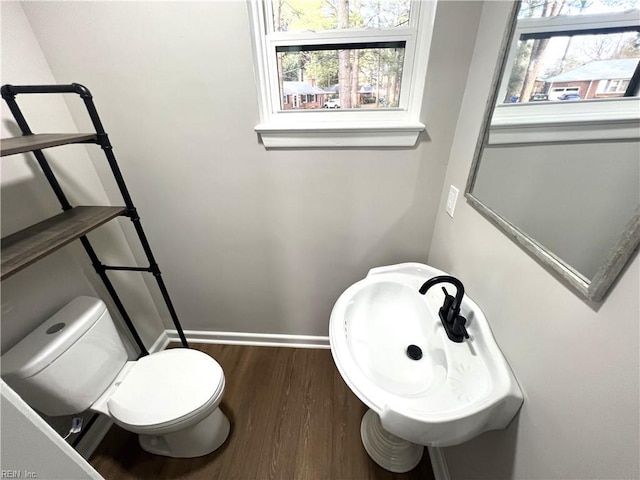 half bath featuring baseboards, toilet, and wood finished floors