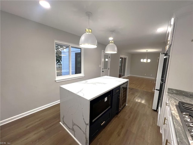 kitchen with dark wood-style floors, dark cabinetry, a kitchen island, and freestanding refrigerator