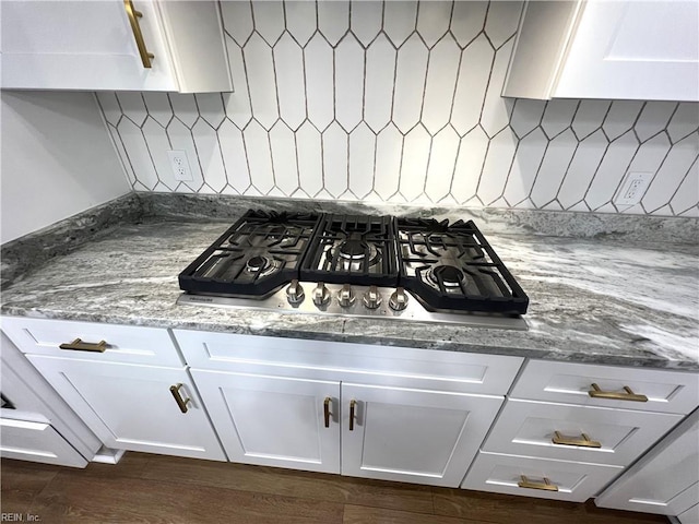 interior details with backsplash, white cabinetry, and stainless steel gas stovetop