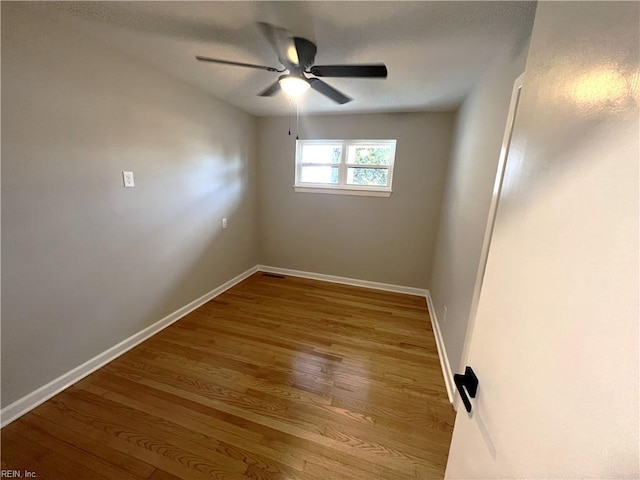 empty room featuring a ceiling fan, baseboards, and wood finished floors