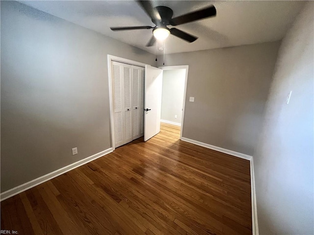 unfurnished bedroom featuring ceiling fan, a closet, wood finished floors, and baseboards