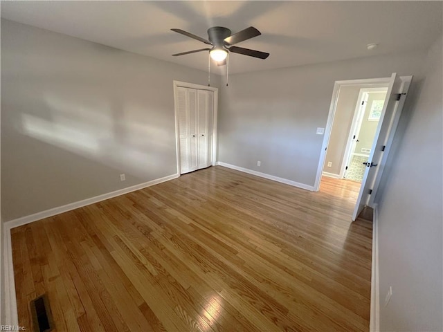 unfurnished bedroom with a closet, visible vents, baseboards, and wood finished floors