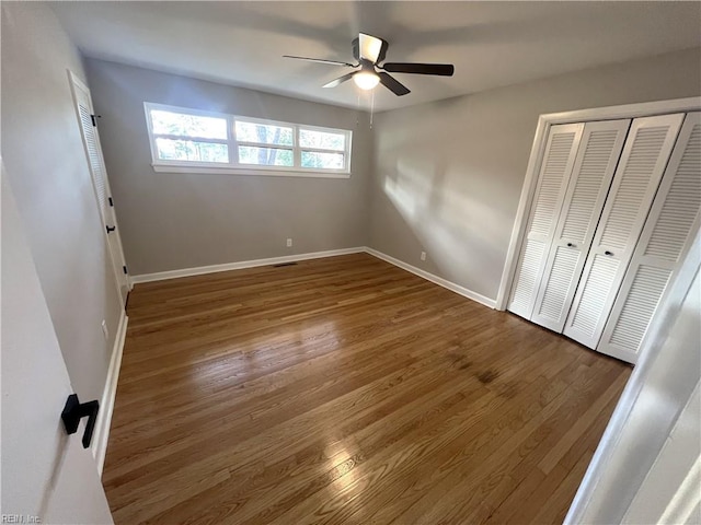 unfurnished bedroom with ceiling fan, a closet, wood finished floors, and baseboards