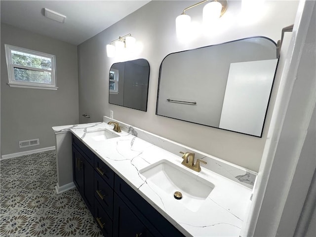 bathroom featuring visible vents, a sink, baseboards, and double vanity