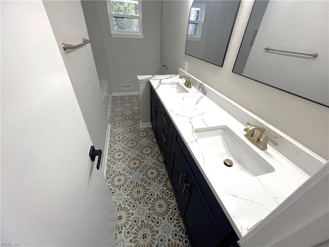 bathroom featuring a sink, baseboards, and double vanity