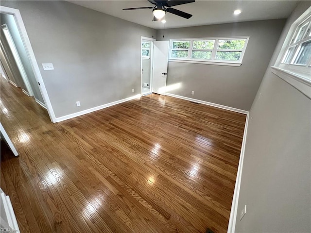 unfurnished room with visible vents, wood-type flooring, a ceiling fan, and baseboards