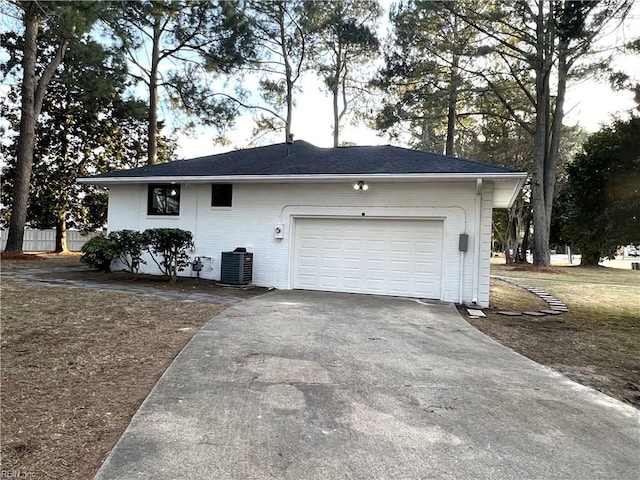 garage featuring driveway, cooling unit, and fence