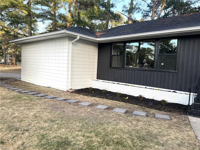 view of side of property featuring a lawn and roof with shingles