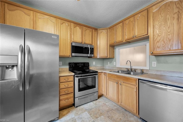 kitchen with a textured ceiling, appliances with stainless steel finishes, light countertops, and a sink