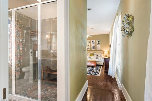 full bathroom featuring wood finished floors, a shower stall, toilet, and baseboards