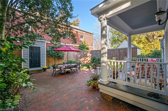 view of patio / terrace featuring a shed, fence, outdoor dining area, and an outdoor structure